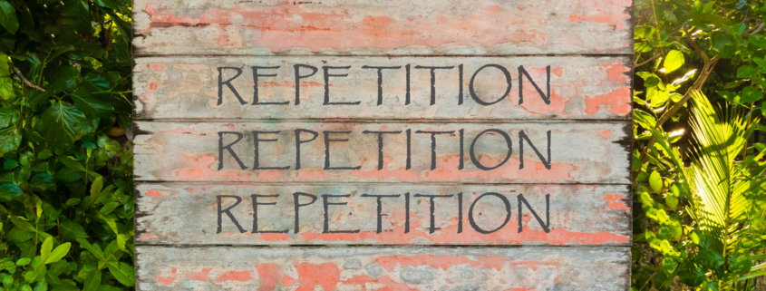 Wooden sign with the word repetition written on it three times with a woodland background
